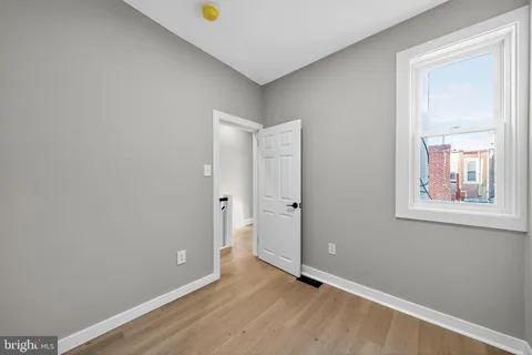 a view of an empty room with window and wooden floor