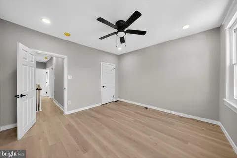 an empty room with wooden floor and ceiling fan