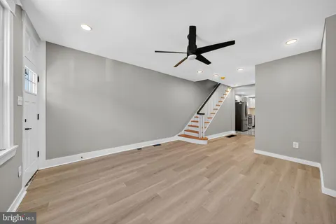 an empty room with wooden floor stairs and windows