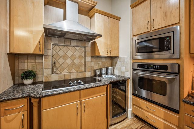 a kitchen with granite countertop a stove top oven microwave and cabinets