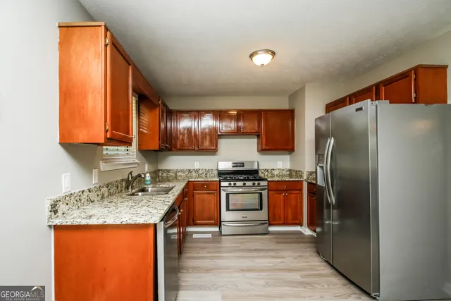 a kitchen with stainless steel appliances granite countertop a refrigerator a stove top oven a sink and dishwasher