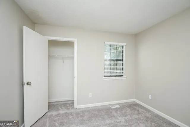 a view of an empty room with closet and a window