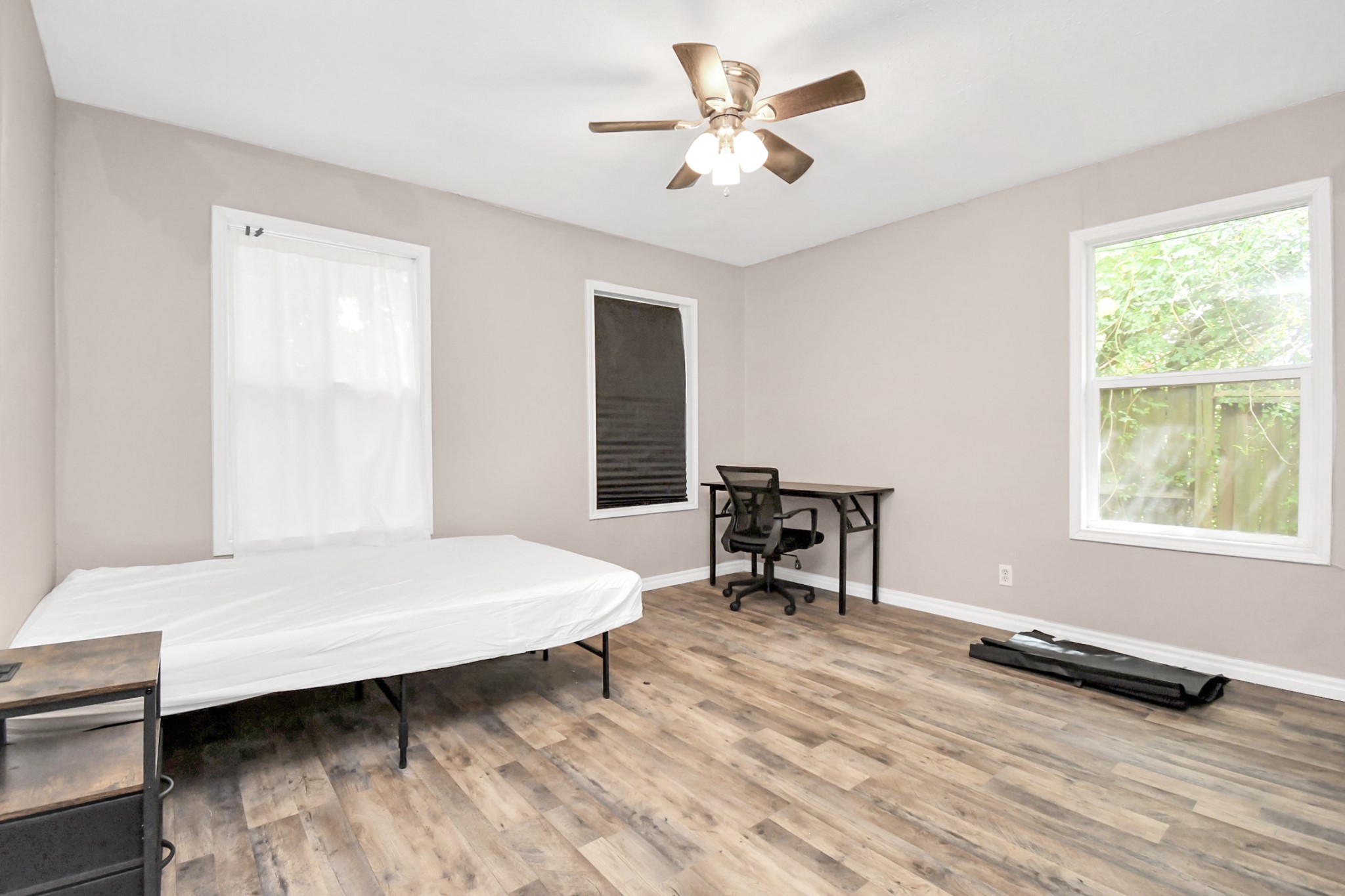 3743 Odin Court Houston, TX 77021 - Photo 24 of 36 Broad window banks showcase the surrounding greenery from this airy bedroom, which features a cooling ceiling fan, closet storage, and a layout optimized for a combination bed-and-desk setup.
