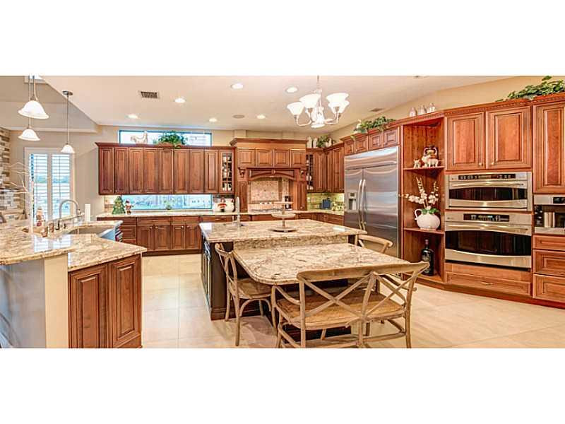 18091 Southwest 66th Street Southwest Ranches, FL 33331 - Photo 12 of 35 a kitchen with stainless steel appliances kitchen island granite countertop a table chairs and a refrigerator