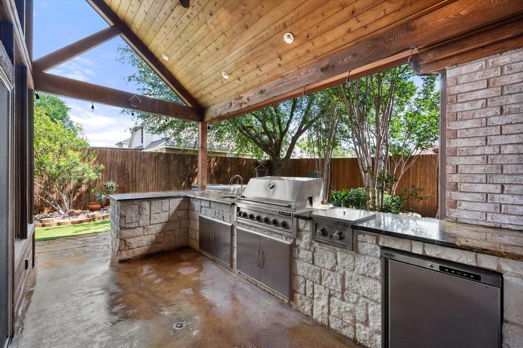 1305 Liverpool Lane Mansfield, TX 76063 - Photo 34 of 40 Outdoor kitchen featuring a stone base, stainless steel appliances, and a wood-paneled ceiling