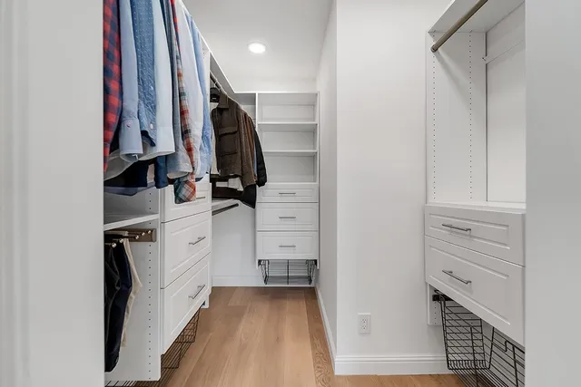 a view of walk in closet with clothes and shoes