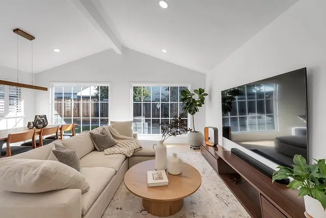 a living room with furniture kitchen view and large windows