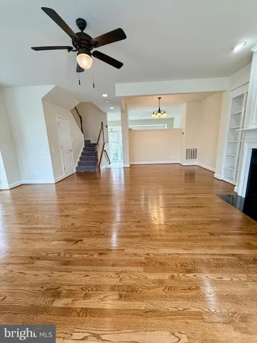 a view of kitchen and empty room with wooden floor