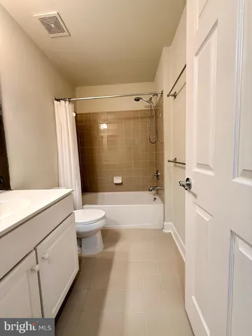 a bathroom with a granite countertop bathtub shower sink vanity and toilet