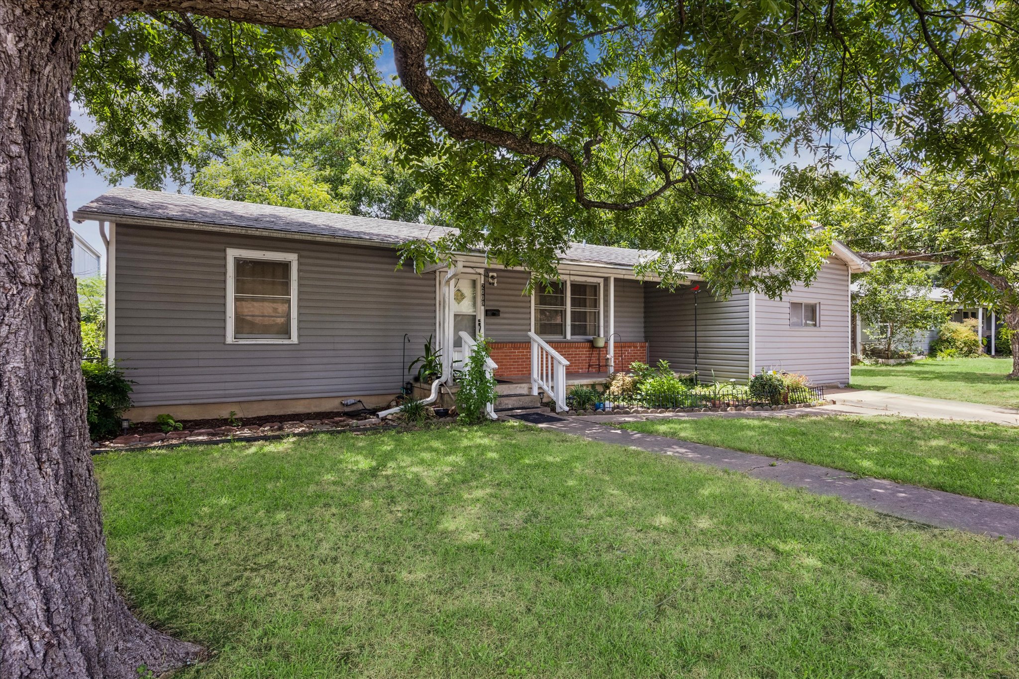 A welcoming front entrance beckons from this charming home with a manicured lawn.