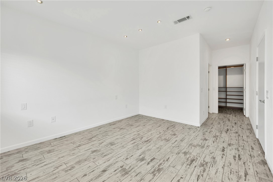 8725 West Flamingo Road, Unit 110 Las Vegas, NV 89147 - Photo 8 of 30 A well-lit bedroom features distressed wood flooring and recessed lighting.