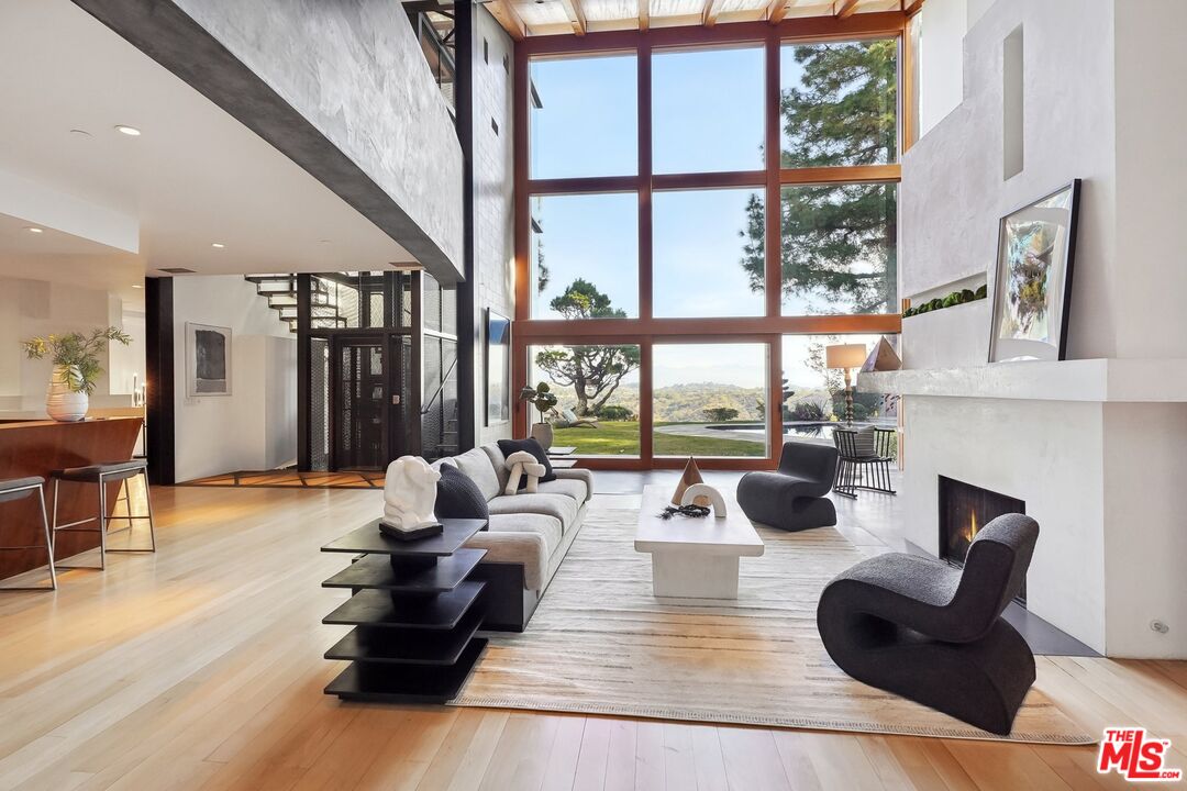 a living room with fireplace furniture and a large window