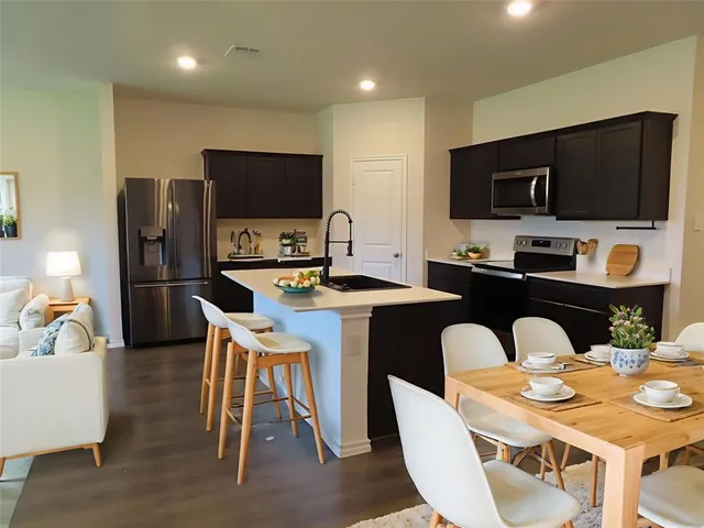 a kitchen with stainless steel appliances kitchen island granite countertop a dining table and chairs