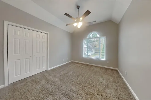an empty room with chandelier fan and windows