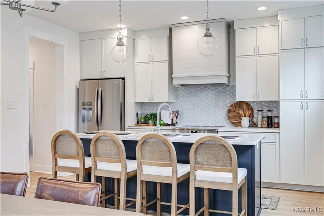 a kitchen with stainless steel appliances granite countertop a dining table chairs refrigerator and sink
