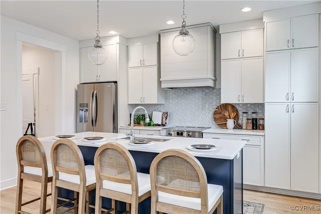a kitchen with stainless steel appliances granite countertop a dining table chairs refrigerator and sink