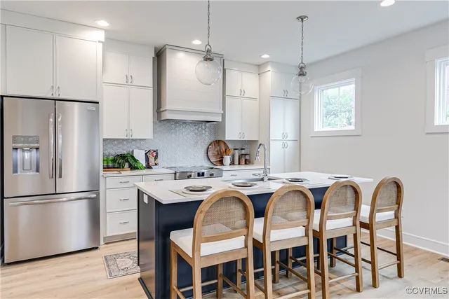 a kitchen with stainless steel appliances granite countertop a dining table chairs refrigerator and sink