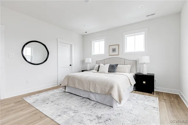 a bedroom with a bed cupboard mirror and window