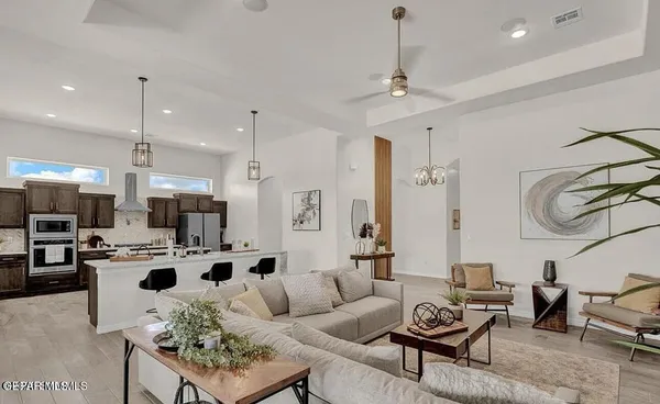 a living room with furniture kitchen view and a chandelier
