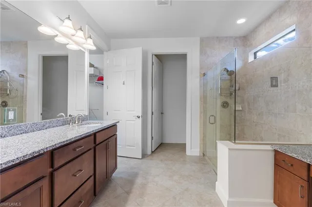 a spacious bathroom with a granite countertop sink a mirror and a shower