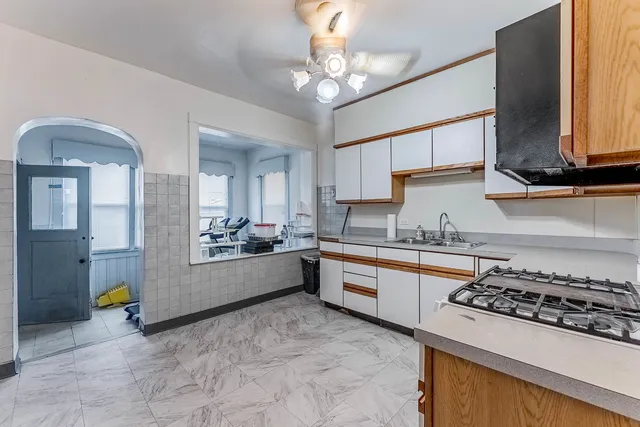 a large kitchen with stainless steel appliances granite countertop a stove a sink dishwasher and white cabinets with wooden floor