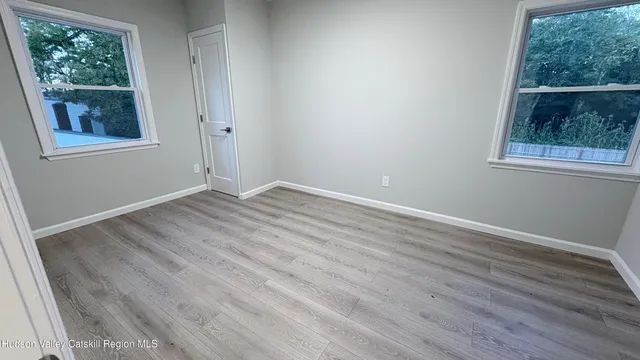 a view of an empty room with wooden floor and a window