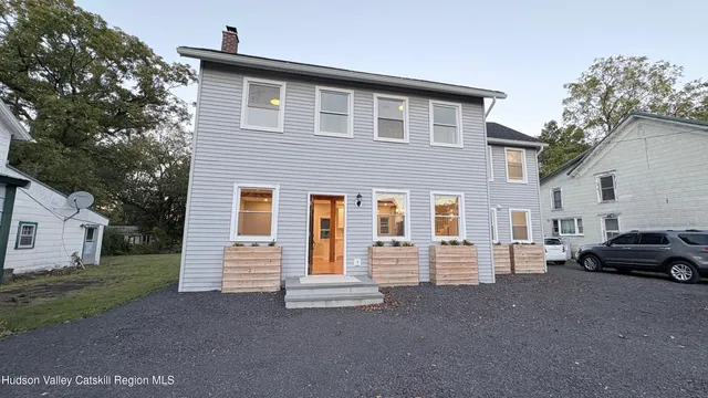 a view of a house with a barbeque and large trees