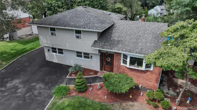 a aerial view of a house with yard and trees in the background