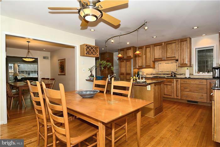 9512 Clement Road Silver Spring, MD 20910 - Photo 7 of 14 a kitchen with stainless steel appliances kitchen island granite countertop a table chairs and a stove top oven with wooden floor