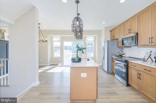a kitchen with stainless steel appliances granite countertop a sink a stove cabinets counter space and living room view