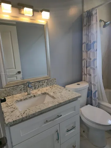 a bathroom with a granite countertop sink toilet and shower