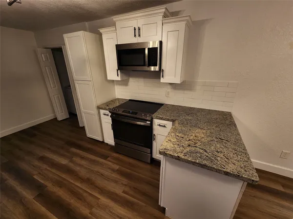 a kitchen with granite countertop a stove and a microwave