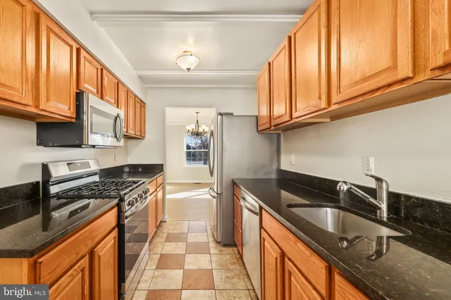 a kitchen with granite countertop stainless steel appliances a sink a stove and cabinets