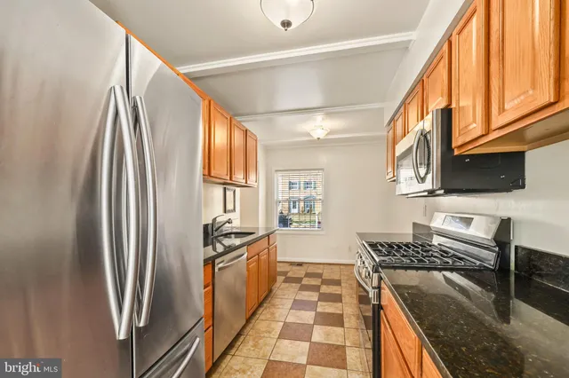 a kitchen with stainless steel appliances granite countertop a refrigerator a stove and a sink with wooden floor