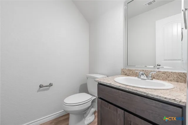 a bathroom with a granite countertop sink a toilet and a mirror