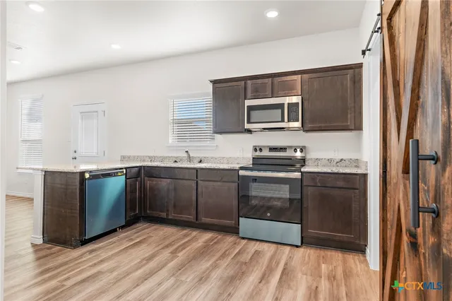 a kitchen with stainless steel appliances granite countertop a refrigerator and a stove top oven