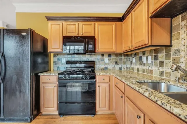 a kitchen with stainless steel appliances granite countertop a stove a sink and a refrigerator