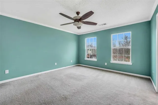an empty room with ceiling fan and windows