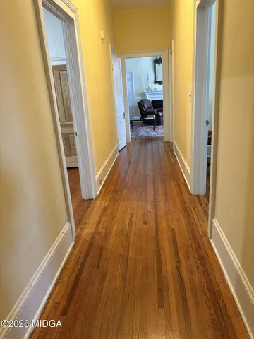a view of a hallway with wooden floor and furniture