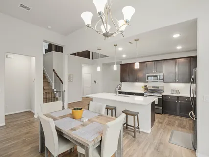 a kitchen with stainless steel appliances kitchen island granite countertop a sink a stove a dining table and chairs