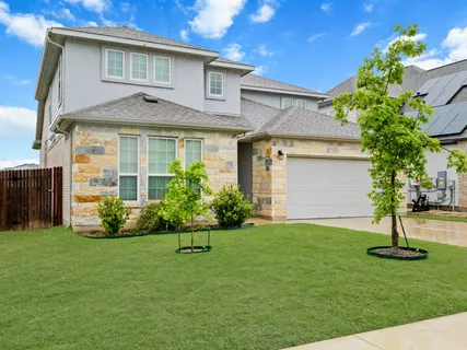 a front view of a house with a yard and trees