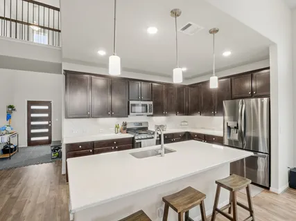 a kitchen with kitchen island a refrigerator and a sink