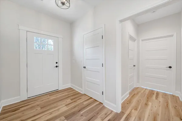 a view of an empty room with wooden floor and a window