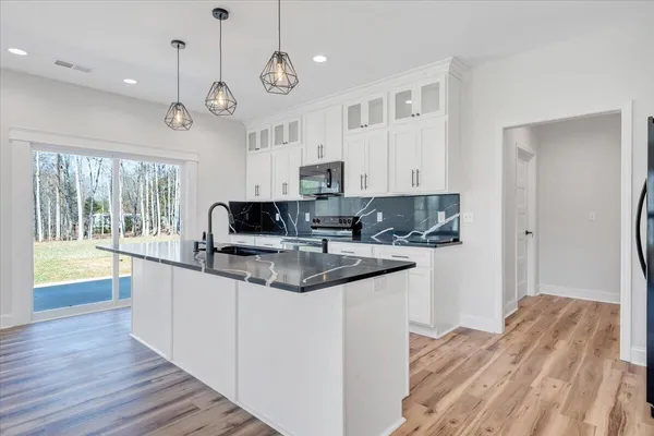 a large kitchen with stainless steel appliances granite countertop a stove and cabinets