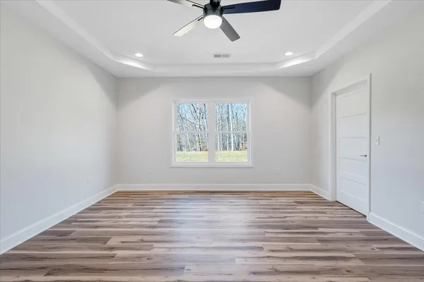 a view of empty room with wooden floor and fan