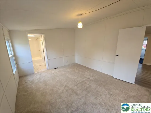 an empty room with an entrance to other room and wooden floor
