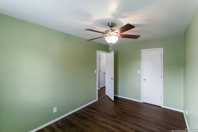 an empty room with wooden floor and a ceiling fan