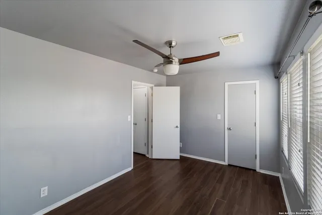 a view of a hallway with wooden floor and a ceiling fan