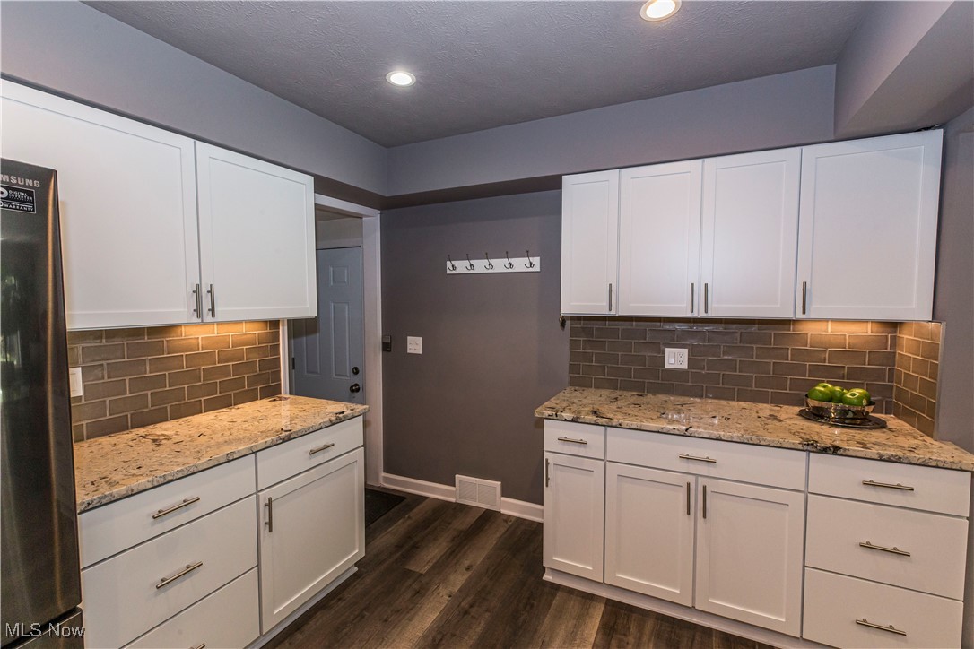 2430 Rockside Road Independence, OH 44131 - Photo 7 of 46 Kitchen with white cabinets, freestanding refrigerator, backsplash, recessed lighting, and a textured ceiling