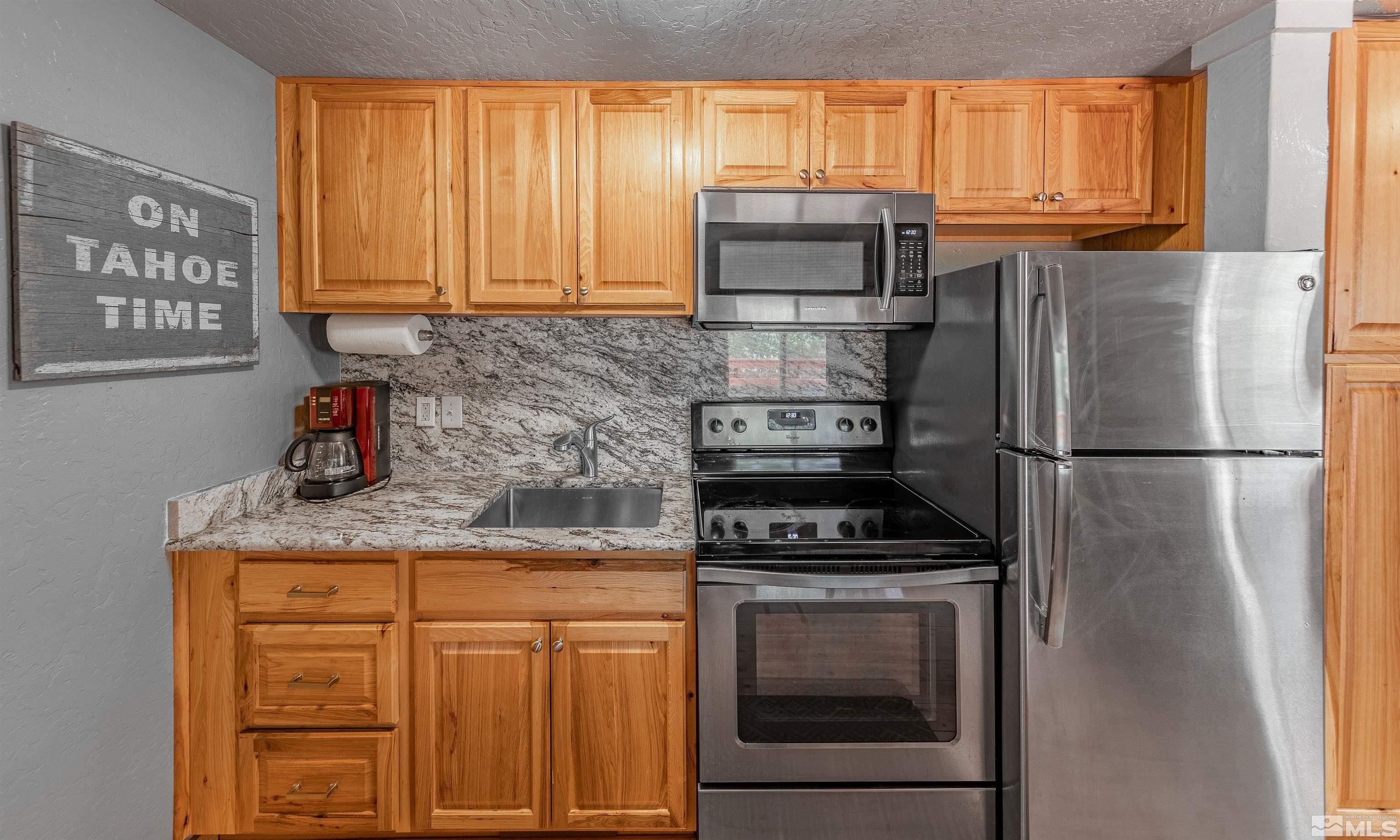 181 Tramway Drive, Unit B Stateline, NV 89449 - Photo 7 of 27 a kitchen with stainless steel appliances granite countertop a refrigerator sink and cabinets